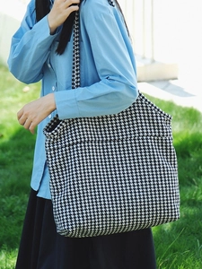 Classic black and white houndstooth tote bag shown in an outdoor casual setting
