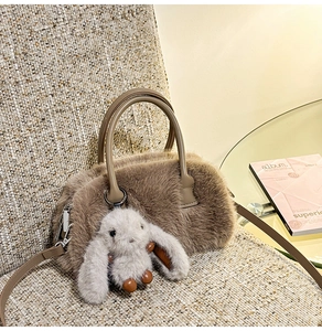 Detail shot of brown faux fur handbag featuring a cute grey rabbit charm and round handles