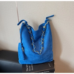 Détail du sac hobo en daim bleu avec chaîne dorée et pochette latérale zippée