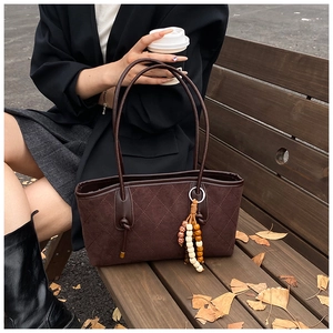 Detail of vintage brown quilted tote bag with bohemian beaded tassel in autumn setting