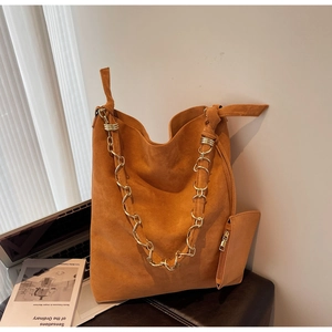 Détail du cabas en daim caramel avec chaîne dorée décorative et poignée nouée élégante