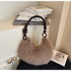 Fuzzy crescent plush bag detail featuring dark woven rope handle and wooden beads decoration
