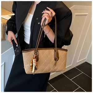 Brown quilted tote bag with retro beaded charm and suede texture shown on a model
