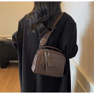 Detail of vintage brown leather crossbody bag with wide nylon strap on model