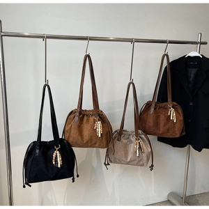 Detalle de bolsos tote con cordón en textura mate con colgantes de cuentas de madera