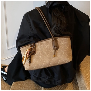 Quilted tote bag detail with suede texture and decorative beaded tassel charm