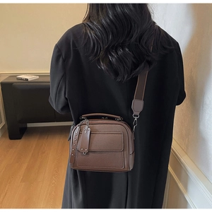 Detail of a brown lychee pattern leather crossbody bag with a wide adjustable strap