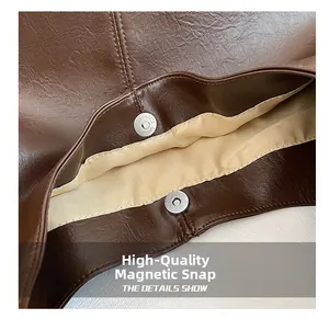 Detail view of the magnetic snap closure on a brown pebble leather tote bag