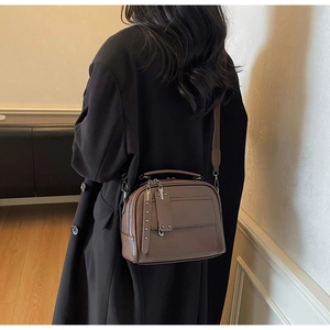 Detail view of brown lychee grain leather crossbody bag with dual zipper puller accents