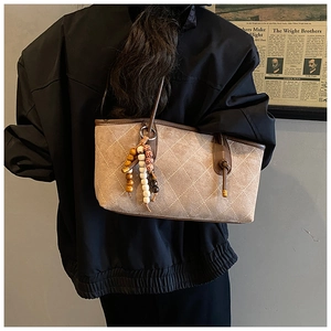 Detail of vintage quilted suede tote bag with bohemian bead charm and leather handles