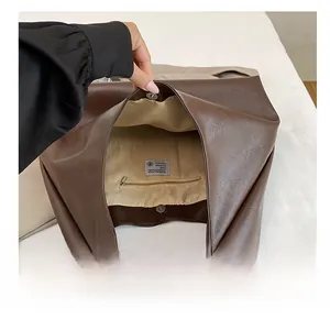 Detail view of large brown tote bag interior with fabric lining and zip pocket