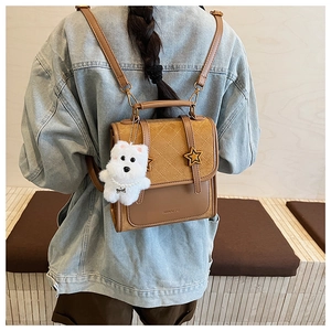 Detail view of retro brown backpack featuring star buckles and white plush puppy charm