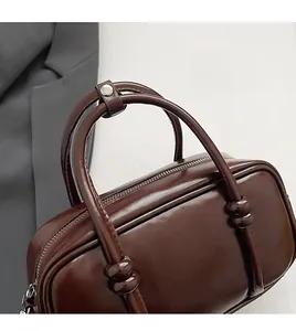 Detail of dark coffee PU leather handbag featuring double handles with silver button strap