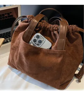 Detalle de bolso tote de ante marrón con bolsillo frontal duradero para el teléfono