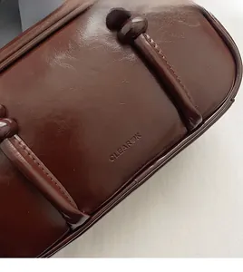 Close-up of CLEAROK embossed logo on dark brown glossy vintage leather bowling bag