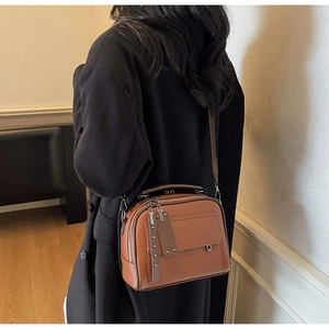 Close-up of brown litchi pattern leather crossbody bag with metal rivet detail