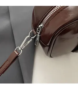Detail of dark brown leather bag showing silver metal hardware and detachable strap