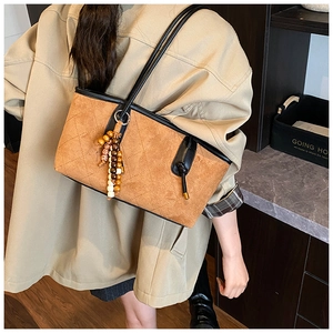 Close-up of quilted brown suede tote bag featuring a wooden bead tassel charm