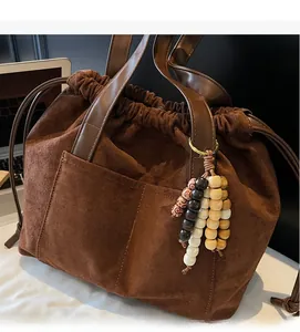 Close-up of brown suede tote bag with drawstring closure and colorful wooden bead charms