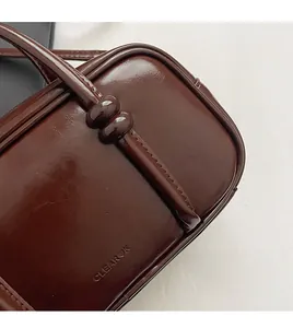 Detail shot of the polished brown faux leather handbag with clean stitching and embossed logo