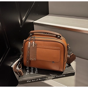 Close-up of brown lychee leather bag texture with double zipper and canvas strap