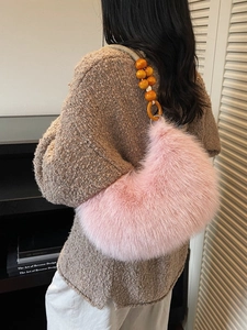 Pink faux fur crescent handbag with yellow beaded strap shown on a model in knitwear