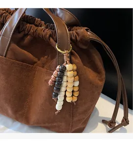 Primer plano del bolso shopper marrón mate con charm de madera y cordón ajustable