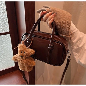 Detail of vintage brown glossy leather Boston bag with cute plush bear charm accessory