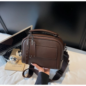 Detail of dark brown litchi pattern leather bag with wide strap and multi-zipper layers