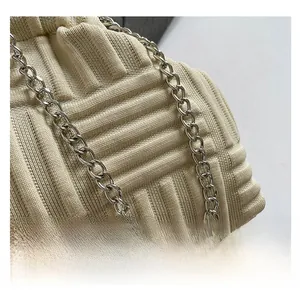 Detalle del bolso de hombro de punto crema con textura 3D y cadena plateada