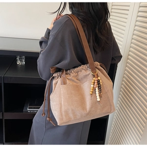 Detalle de bolso tote de ante color avena con cordón ajustable y cuentas de madera