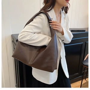 Detail view of large dark brown leather tote bag showing seam stitching and matte texture