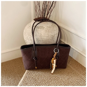 Close-up of retro quilted brown tote bag with beaded tassel and suede texture detail