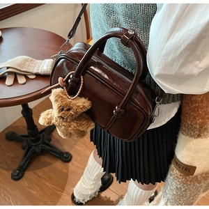 Detail of vintage dark brown polished Boston bag with cute plush bear charm accessory