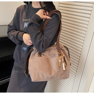 Macro detail of brown faux suede hobo bag featuring drawstring and wooden bead tassel