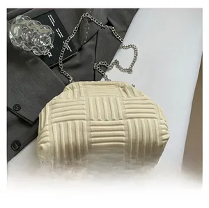 Detalle de bolso tipo concha trenzado beige con cadena plateada y fondo de moda chic