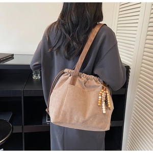 Detail of khaki suede drawstring tote bag with beaded pendant and leather strap