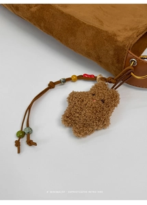 Detail of suede tote bag with plush star charm and colorful beaded tassel accessory