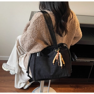 Detail of black suede tote bag featuring drawstring closure and ethnic beaded charms