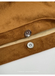 Detailed close-up of a silver magnetic clasp on a brown suede commuter tote bag