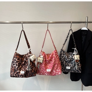 Detailed view of leopard print canvas tote bags in brown, pink, and grey with plush charms