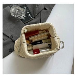 Detail view of cream knitted crossbody bag showing spacious interior with personal essentials