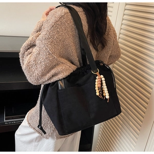 Detail of black suede tote bag with leather straps and decorative colorful beads