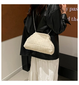 Detail of off-white woven pouch bag with silver chain strap worn by a model