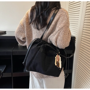 Detailed view of black suede bucket bag with decorative beads on a female model