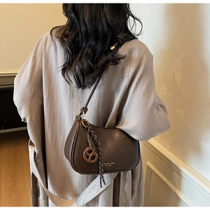 Detail of dark brown semi-circle crossbody bag with polished leather and gold logo