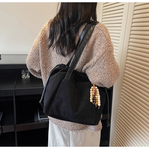 Detail of black suede tote bag with colorful wooden bead charm and drawstring closure