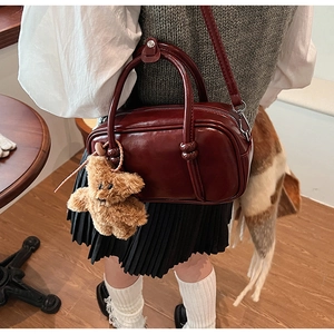 Detail of vintage wine red PU leather bowling bag with cute brown bear charm