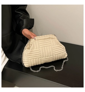 Detail of cream-white woven clutch bag featuring soft texture and silver chain strap