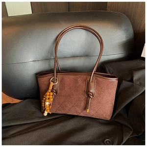 Detail of dark brown quilted suede tote bag with wooden bead tassel and tied handles